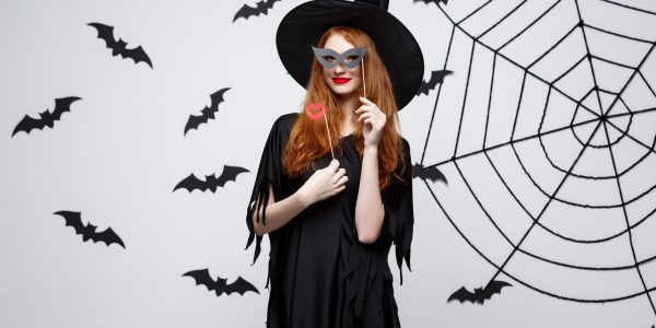 Halloween concept - Beautiful girls in black witch dresses holding party props