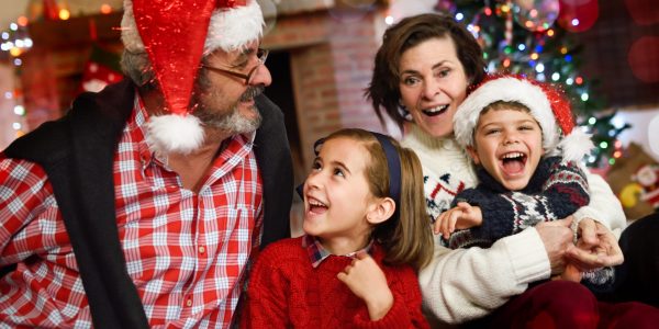 Grandparents playing with grandchildren in their living room decorated for Christmas